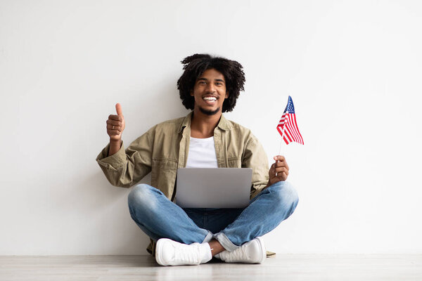 Happy Young Black Guy Sitting On Floor With Laptop And American Flag
