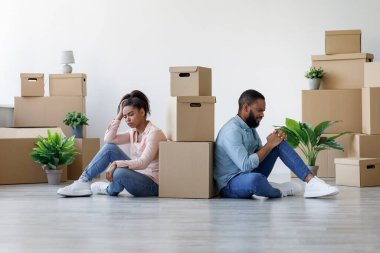 Mutsuz genç siyahi adam ve bayan yorgun ve apartmanda kutularla oturuyorlar.