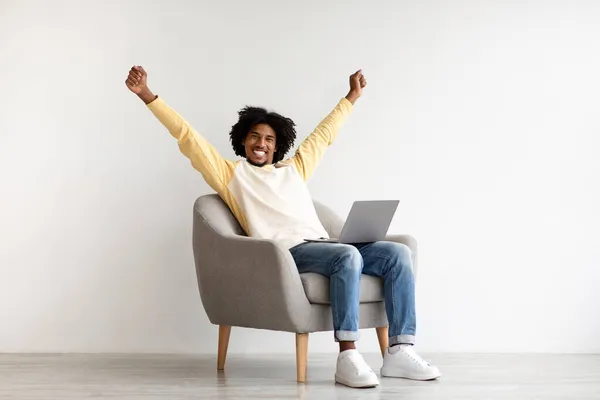 Carreira Freelance. animado feliz preto masculino sentado no poltrona com laptop — Fotografia de Stock