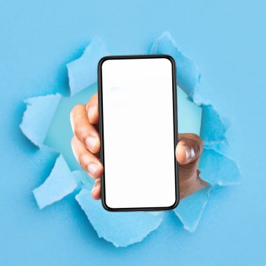 Siyah adam beyaz ekranlı akıllı telefonu yırtık mavi kağıtta delik deşik ederek, uygulama veya web sitesi için model alarak gösteriyor