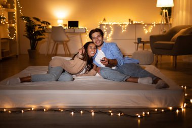 TV 'de keyifli bir film seyreden çift Evdeki Yatakta Yatıyor