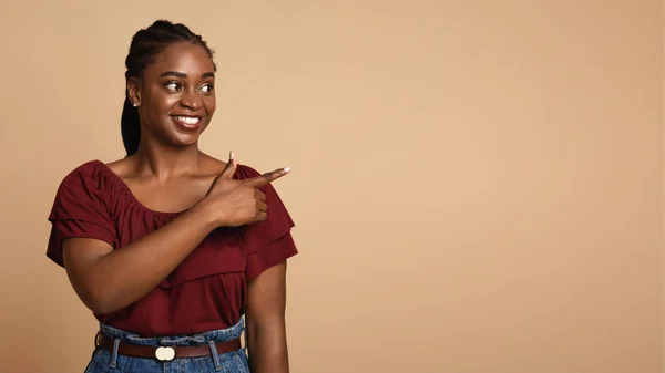 Привлекательная африканская американка показывает рекламу на бежевом — стоковое фото