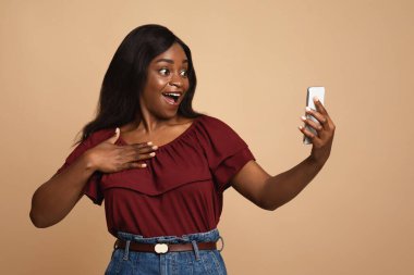 Şaşırmış siyah kadın arkadaşlarıyla görüntülü konuşma yapıyor.