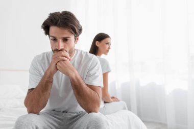 Sakallı, bunalımlı, genç, beyaz bir koca yatakta üzgün, yatak odasındaki gücenmiş bayanı görmezden geliyor.