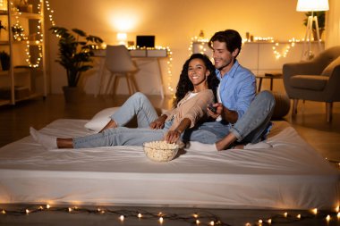 Televizyon seyreden ve evde patlamış mısır yiyen çift.