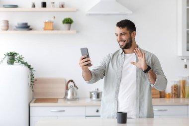 Çevrimiçi kahve içen, gülümseyen, beyaz bir erkek, uzaktan toplantı yapıyor.