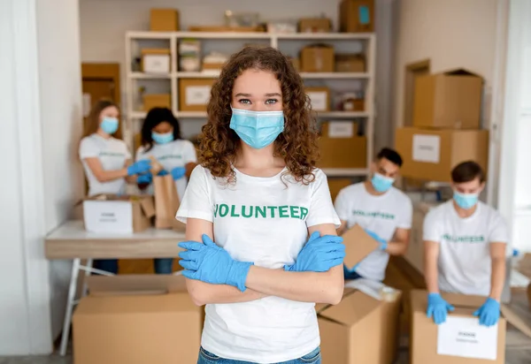 Centro de caridad. Joven voluntaria en máscara médica posando con las manos cruzadas, trabajando en organización de voluntariado —  Fotos de Stock