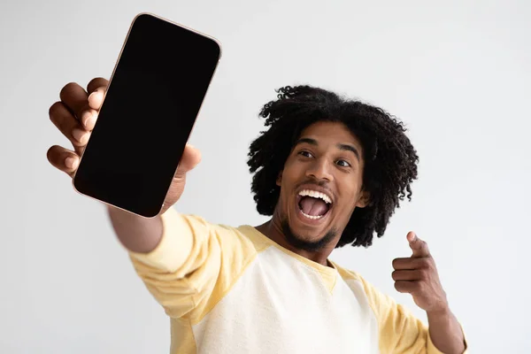 Cool App. Emocionado Negro Hombre Demostrando Smartphone con pantalla grande en blanco, Mockup — Foto de Stock