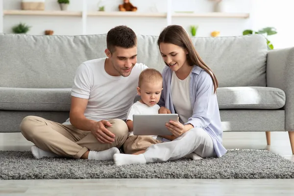 Tempo libero in famiglia. Genitori millenari con il figlio del bambino che utilizza la tavoletta digitale a casa — Foto Stock