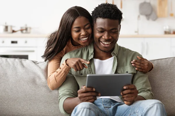 Vrolijk Afrikaans Amerikaans paar plezier hebben thuis, met behulp van pad — Stockfoto