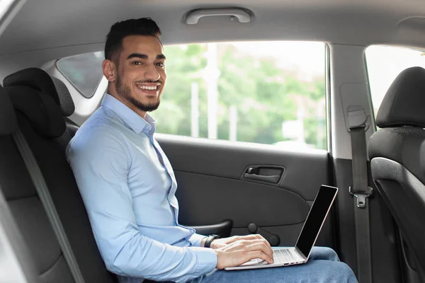 Snygg arabisk entreprenör sitter på auto, med bärbar dator, mockup — Stockfoto