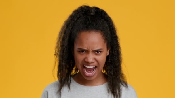 Разгневанная чернокожая девушка кричит на желтом фоне — стоковое видео