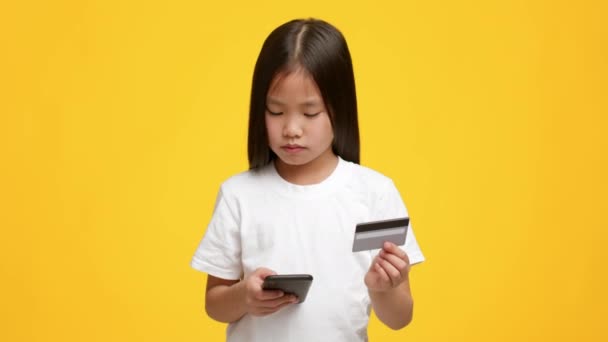 Little Japanese Girl Compras con Smartphones y Tarjeta de Crédito, Estudio — Vídeo de stock