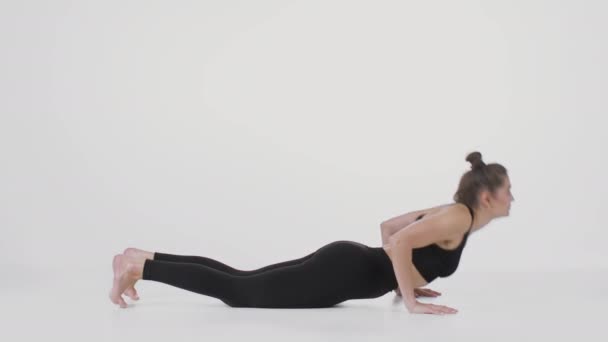 Cobra positie. Side view shot van flexibele vrouw uitvoeren van rug stretching oefening, oefenen over witte achtergrond — Stockvideo