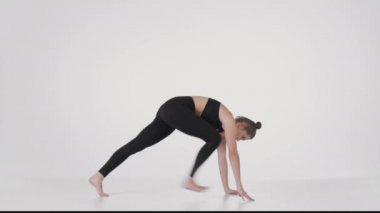 Trikonasana ve Downward Dog pozları üzerinde çalışan genç esnek, beyaz stüdyo arka planı üzerinde onu geriyor