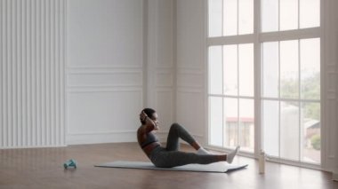 Sportif siyahi kadın, dirsek dirseğe, karın kası egzersizi yapıyor, evde antrenman yapıyor.