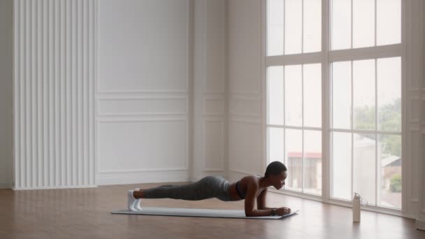 Atletische jonge zwarte vrouw maken Plank Oefening tijdens de training thuis — Stockvideo