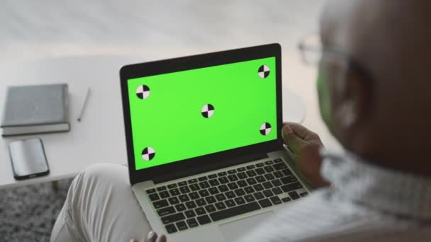 Över axeln syn på oigenkännlig senior afrikansk amerikansk man tittar på tv jon bärbar dator med grön chroma nyckel skärm — Stockvideo