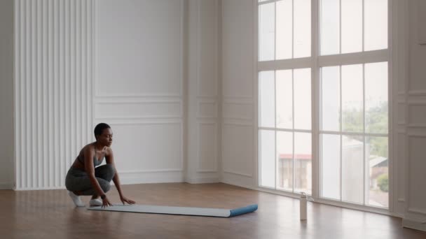 Готовлюсь к тренировкам. Спортивная молодая африканская американка разворачивает коврик для фитнеса — стоковое видео