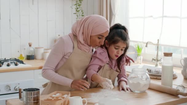 Arabe mère et fille à l'aide de farine faisant la pâte dans la cuisine — Video