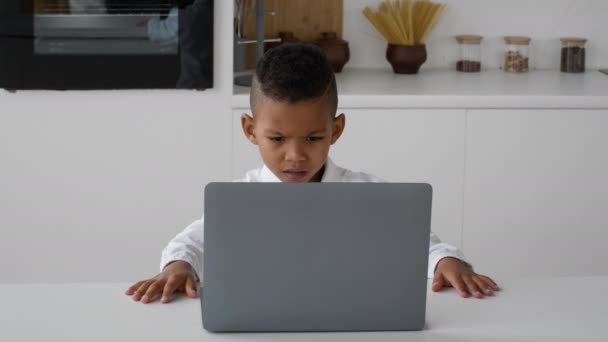 Estudo do menino preto com laptop em casa, franzindo enquanto olha para a tela — Vídeo de Stock