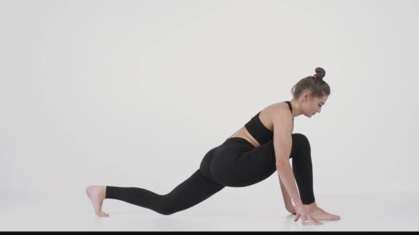 Sportig livsstil. Ung kvinna övar pilates utbildning, sträcker på ryggen och står i nedåtgående hund position — Stockvideo