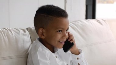 Telefon var. Neşeli küçük siyah çocuk cep telefonuyla konuşuyor, yakın plan.