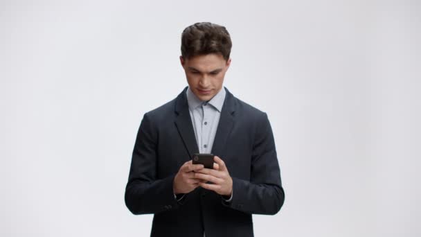 La vie en ligne. Jeune homme d'affaires en costume formel bavardant sur smartphone, lisant des nouvelles ou communiquant avec des partenaires — Video