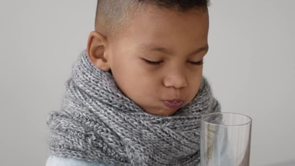 Pequeño chico negro usando cuello bufanda de la cabeza Beber agua limpia de vidrio — Vídeos de Stock