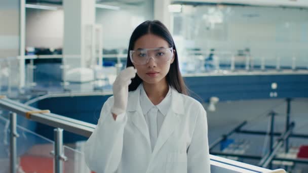 Científica coreana que usa gafas protectoras, abrigo de laboratorio blanco interior — Vídeos de Stock