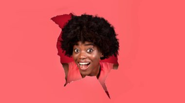 Şok olmuş siyah kadın kağıt deliğinden bakıyor.