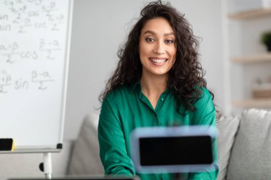 Öğretmen öğrencilere matematiği açıklıyor, akıllı telefondan video kaydediyor.