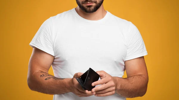 Irreconocible infeliz triste adulto europeo hombre en blanco camiseta mira la cartera vacía, preocuparse por la quiebra — Foto de Stock