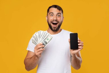 Ağzı açık, heyecanlı, beyaz tenli bir adam kazanmaktan mutluluk duyar, bir sürü dolar tutar ve boş ekranlı akıllı telefon kullanır.