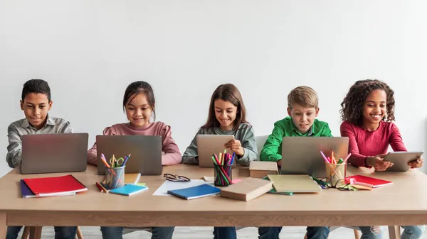 Multikulturális iskolás gyerekek Laptop számítógéppel tanulnak az osztályteremben, Panoráma — Stock Fotó