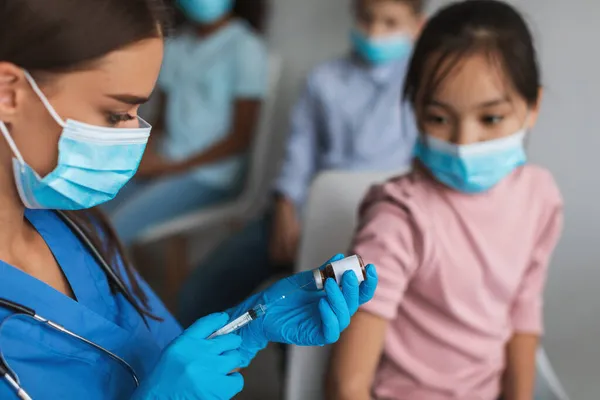 Trabajador médico vacunando a una niña preadolescente china inyectando la vacuna contra el Coronavirus en interiores — Foto de Stock