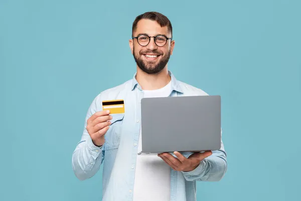 Fröhlich reifer Kaukasier in Brille mit Laptop, Kreditkarte empfiehlt Einkauf aus der Ferne während covid-19 — Stockfoto