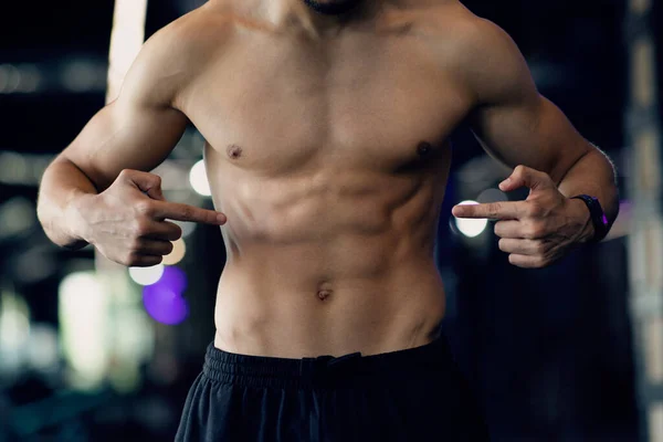 Muscoloso giovane uomo con torso nudo che indica muscoli addominali malati — Foto Stock