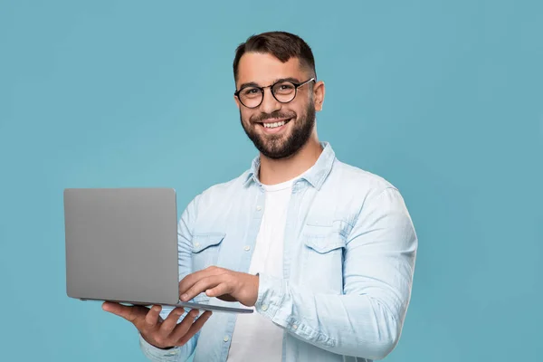 Sorrindo homem caucasiano adulto em óculos trabalhando no laptop, conversando em redes sociais e verificando o correio — Fotografia de Stock