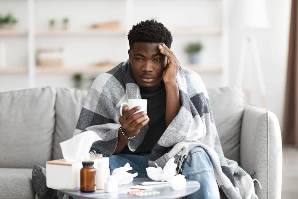 Hombre negro molesto teniendo gripe, bebiendo té caliente — Foto de Stock