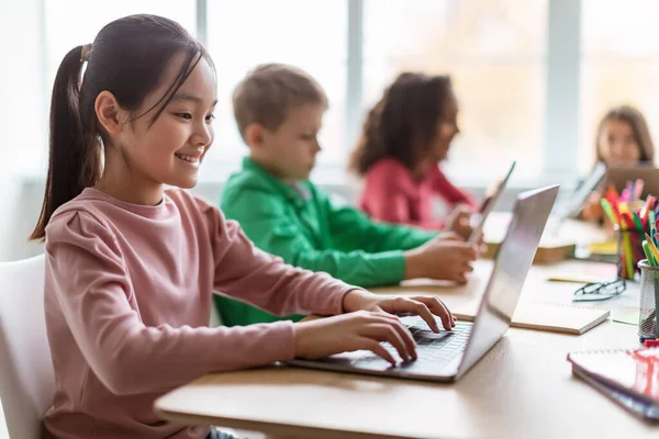 Diverse kinderen leren met behulp van laptop in moderne klaslokaal op school — Stockfoto