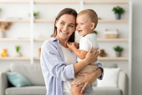 Feliz hermosa joven madre acurrucando su adorable bebé bebé hijo en casa —  Fotos de Stock