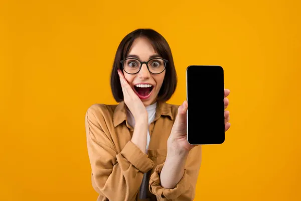 Buena aplicación. Mujer muy alegre demostrando teléfono inteligente con pantalla en blanco, mostrando espacio para el diseño de su sitio web — Foto de Stock