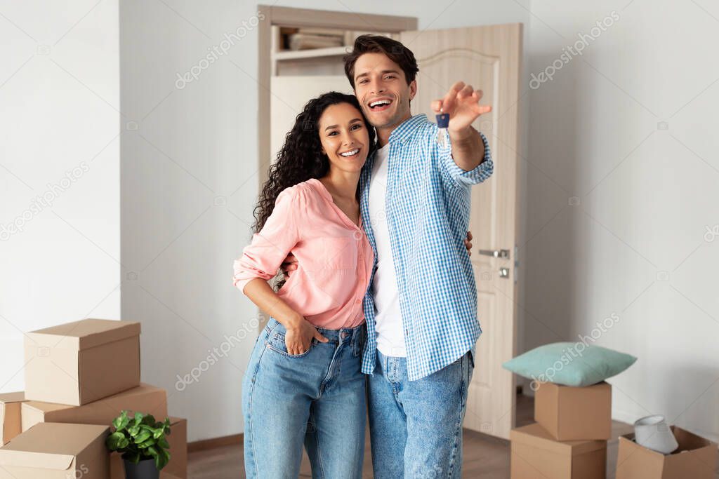 Happy couple showing keys from flat on moving day