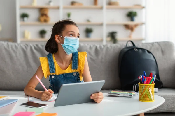 Fată tristă în mască medicală care studiază acasă cu tabletă — Fotografie, imagine de stoc