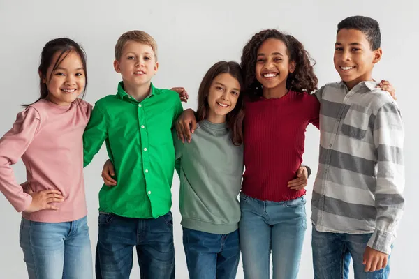 Vidám multikulturális Preteen Kids álló pózol együtt a szürke háttér — Stock Fotó