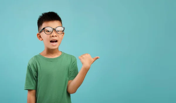 Überprüfen Sie dies. Kleiner asiatischer Junge in Brille zeigt mit erhobenem Daumen zur Seite — Stockfoto