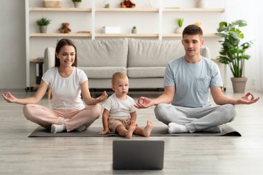 Çevrimiçi yoga. Küçük çocuklu mutlu bir aile dizüstü bilgisayarla meditasyon yapıyor.