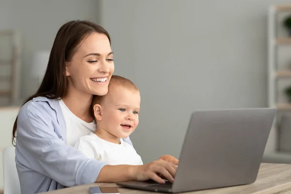 Retrato de mãe feliz com pouco bebê em mãos usando laptop juntos — Fotografia de Stock