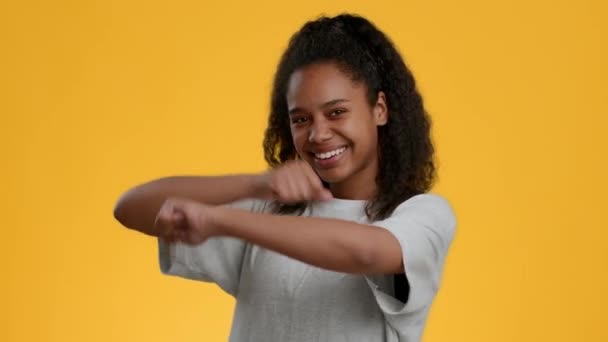 Чернокожая девушка танцует, смеясь над желтым фоном — стоковое видео